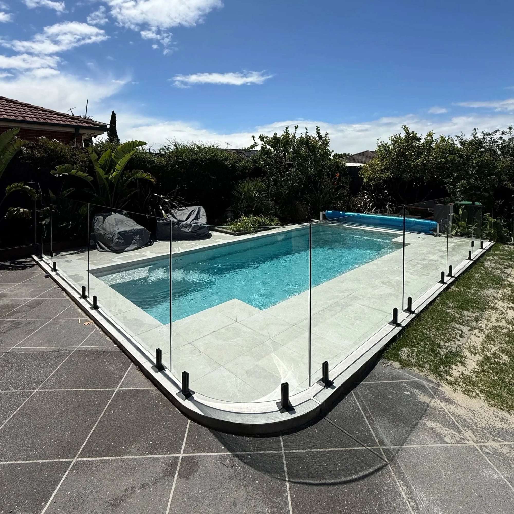 Frameless glass pool fence with a rounded corner around a pool