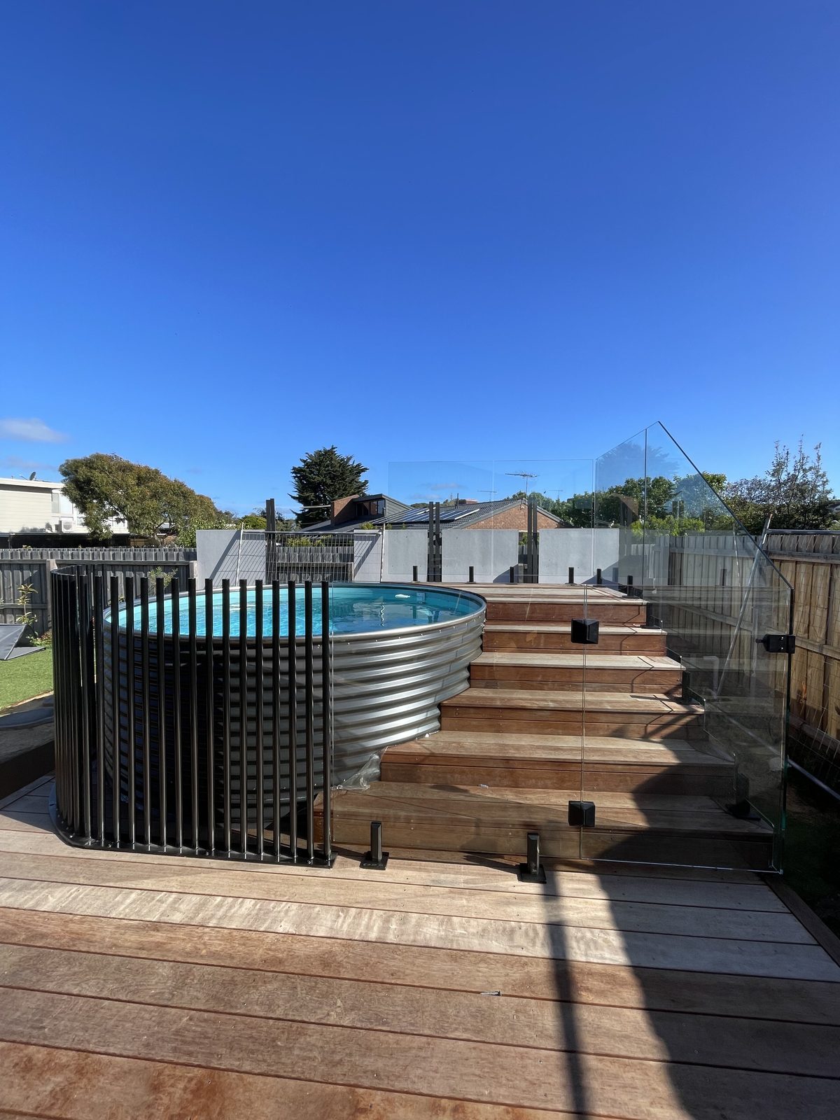 Black rod and glass fence around a plunge pool on a timber deck